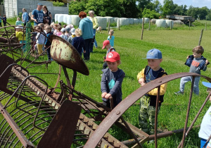 Chłopcy oglądają dawne maszyny rolnicze.